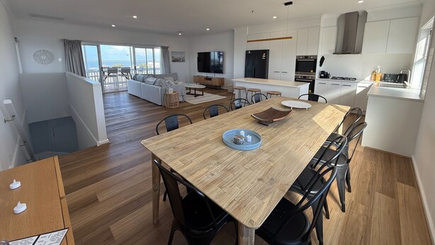 A modern apartment with a dining area, kitchen, and a balcony with a view. - Sea Escape - Sea Views!  Short walk to Tavern! Off Peak Special available! (Point Turton)