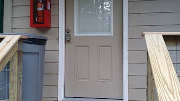 A front door with a 'No Smoking' sign, a fire extinguisher, and a mailbox.