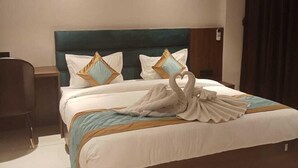 A hotel room with a large bed, two pillows, a headboard, a bedside table, and a chair. - Hotel Kamakhya Inn (Chhatarpur)