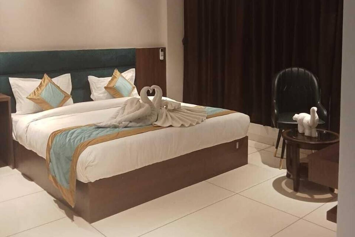 Una habitación de hotel moderna con una cama grande, un ventilador de techo y una cortina oscura.