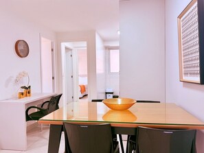 Un espace repas moderne avec une table à plateau en verre, des chaises noires et un élément décoratif central en fibres tressées.