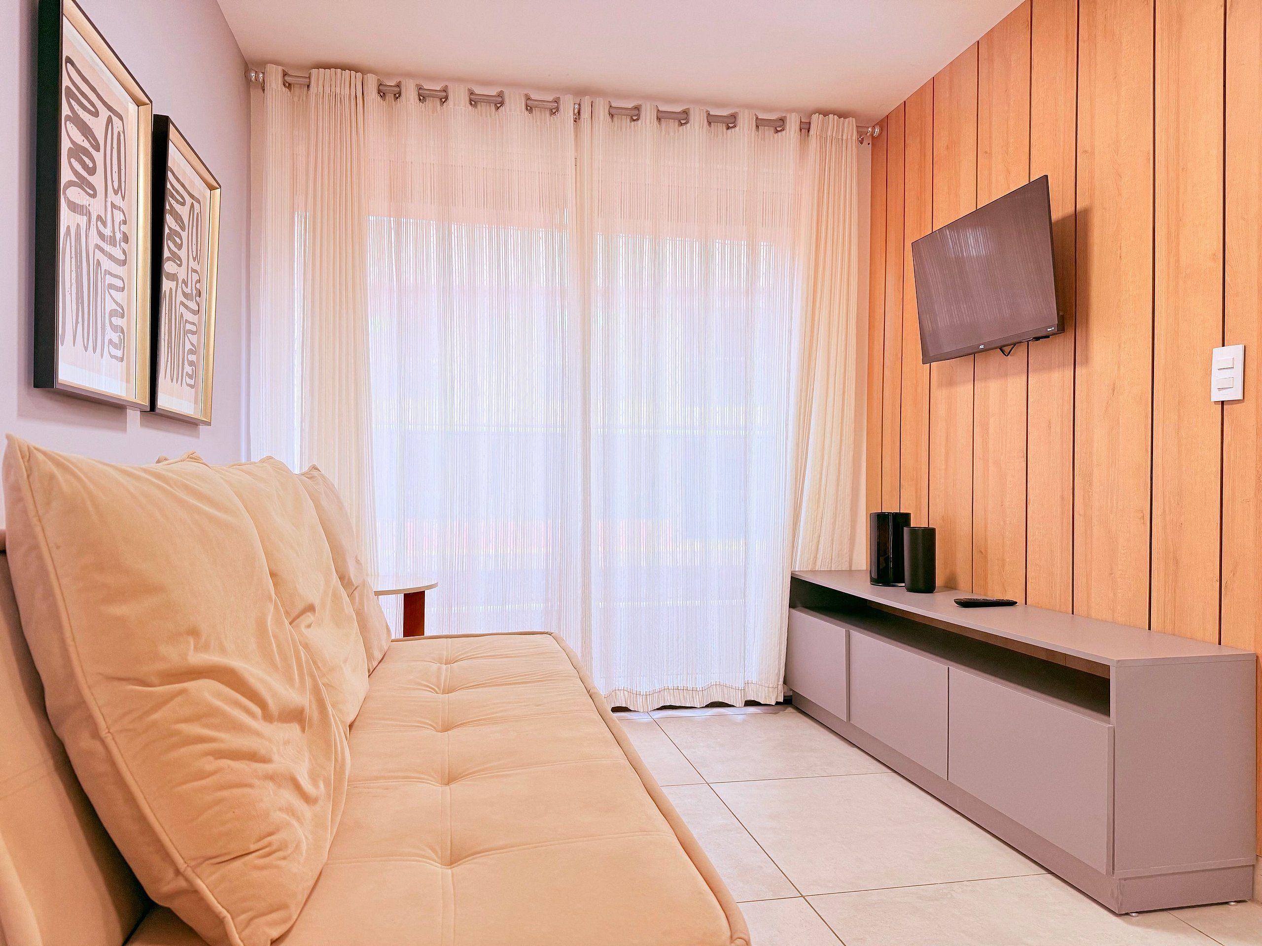 Una sala de estar moderna con un sofá, un televisor montado en la pared y un mueble de madera.