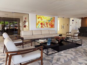 A modern lobby with a sofa, armchairs, a coffee table, and a large abstract painting.