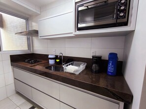 Una cocina equipada con microondas, estufa, lavaplatos y cafetera.