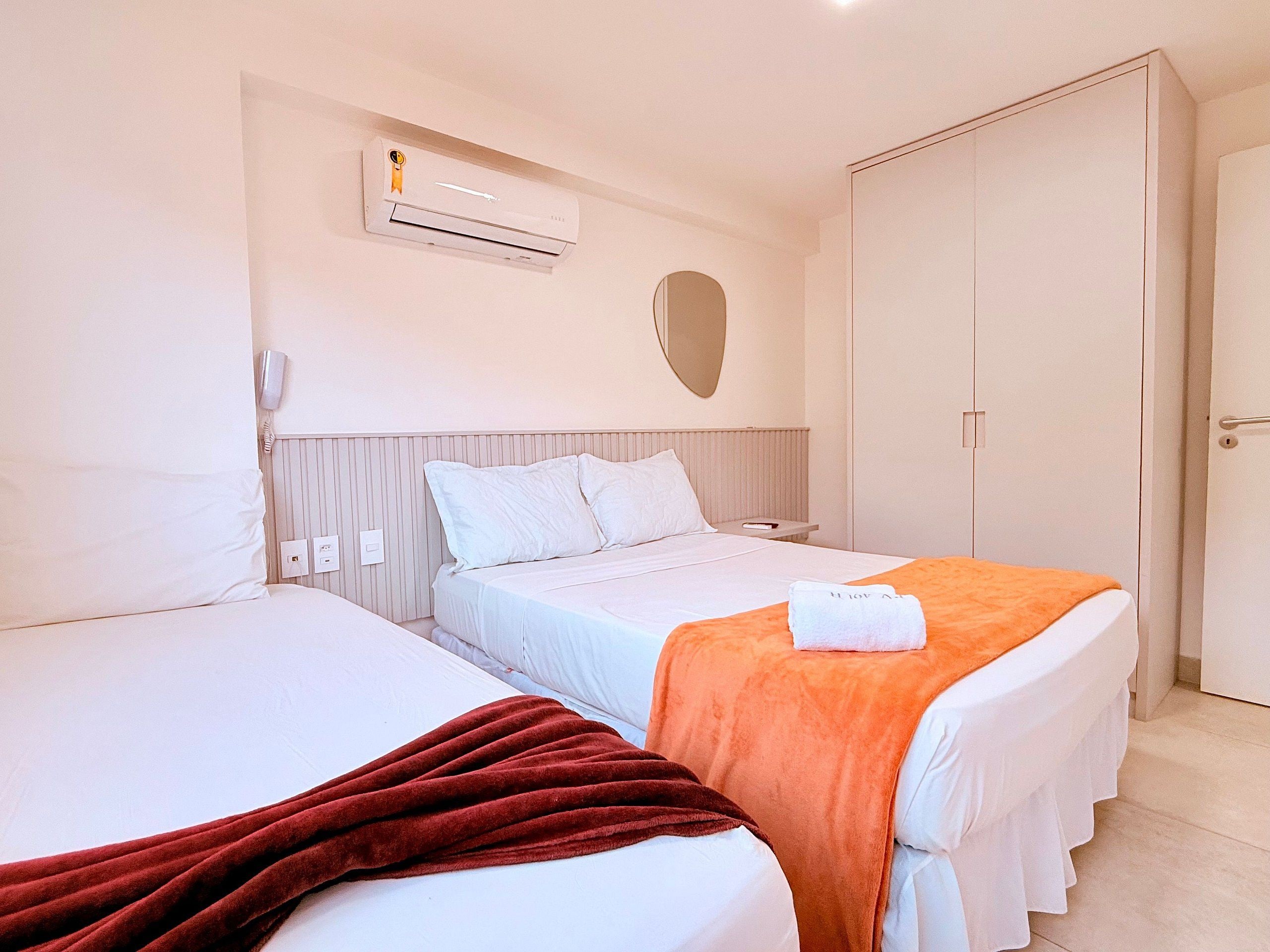 Habitación de hotel con dos camas, un equipo de aire acondicionado, teléfono en la mesita de noche y un armario.