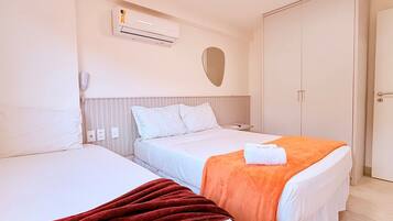 Habitación de hotel con dos camas, un equipo de aire acondicionado, teléfono en la mesita de noche y un armario.