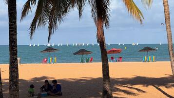 Una playa con palmeras, sillas y sombrillas.