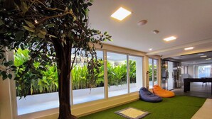 A modern interior with a large window, artificial greenery, and a seating area.