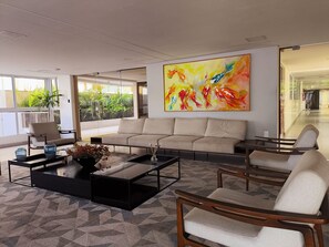 Un salon moderne comprenant un canapé, des fauteuils, une table basse et un grand tableau abstrait.