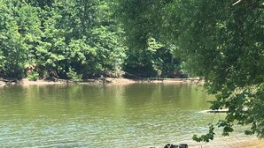 A serene lakeside scene with a dirt path leading to a wooden structure by the water.