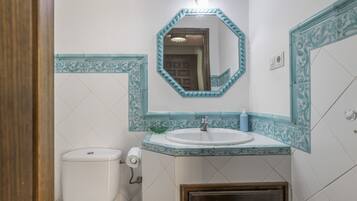 Une salle de bain avec des toilettes, un lavabo et un miroir.