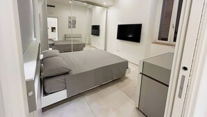 Un dormitorio moderno con cama, televisor y espejo.