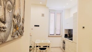 Una cocina compacta con comedor, una ventana con persianas y una puerta.