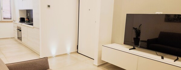 A modern living room with a flat-screen TV, a sofa, and a small coffee table.
