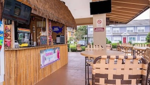 A tiki bar with a thatched roof, a Bud Light sign, and a menu board. There are outdoor tables and chairs. - Charming 3brtownhome Near Disney (Kissimmee)