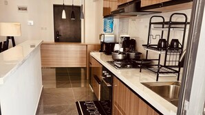 A modern kitchen with wooden cabinets, a marble countertop, a stove, and a sink. There are black hanging lights and a black and white kitchen mat on the floor. - Exquisite 2-bedroom with 3 beds in Riverside, Nairobi (Nairobi)