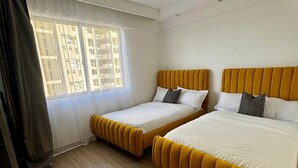 A hotel room with two beds, a window with curtains, and a ceiling light. - Exquisite 2-bedroom with 3 beds in Riverside, Nairobi (Nairobi)
