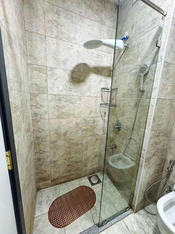 Une cabine de douche fermée par des parois en verre, équipée d’un pommeau de douche à main et d’un pommeau de douche fixé au mur.