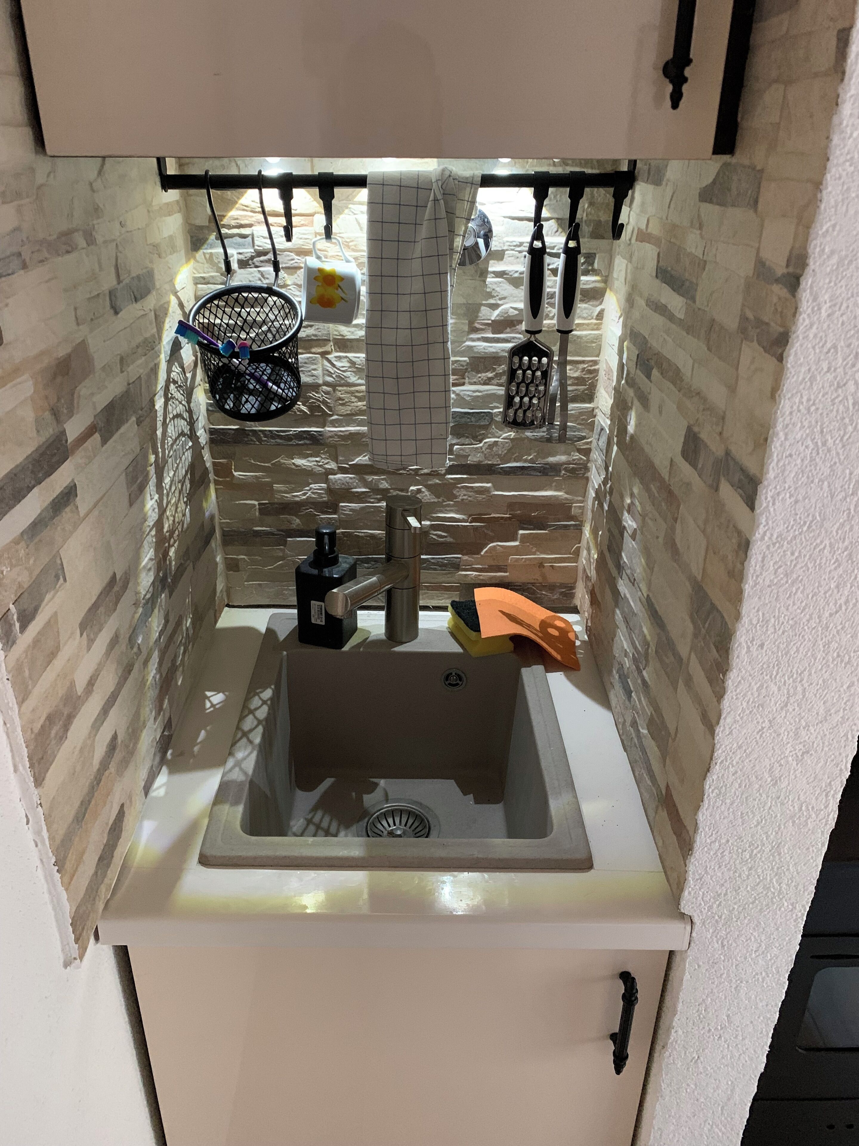 Cozinha com pia, cesto pendurado e painel de azulejos.