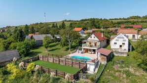 A residential area with houses, a swimming pool, and a hill in the background.