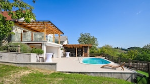 Une maison moderne dotée d’une piscine, d’un espace salon extérieur et offrant une vue sur la campagne.