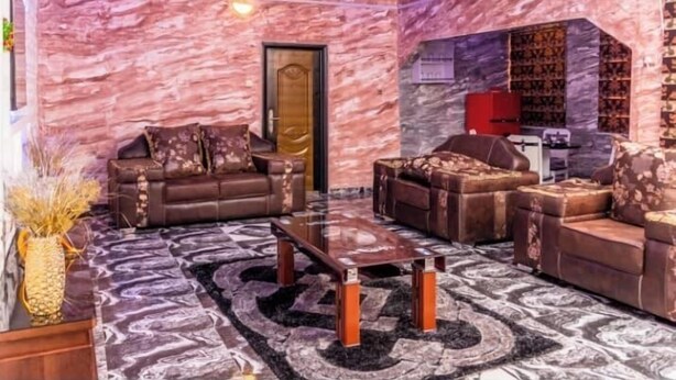 A modern living room with a marble wall, two leather sofas, a coffee table, and a bookshelf. - Eagle Destiny Hotel and Apartment  (Asaba)