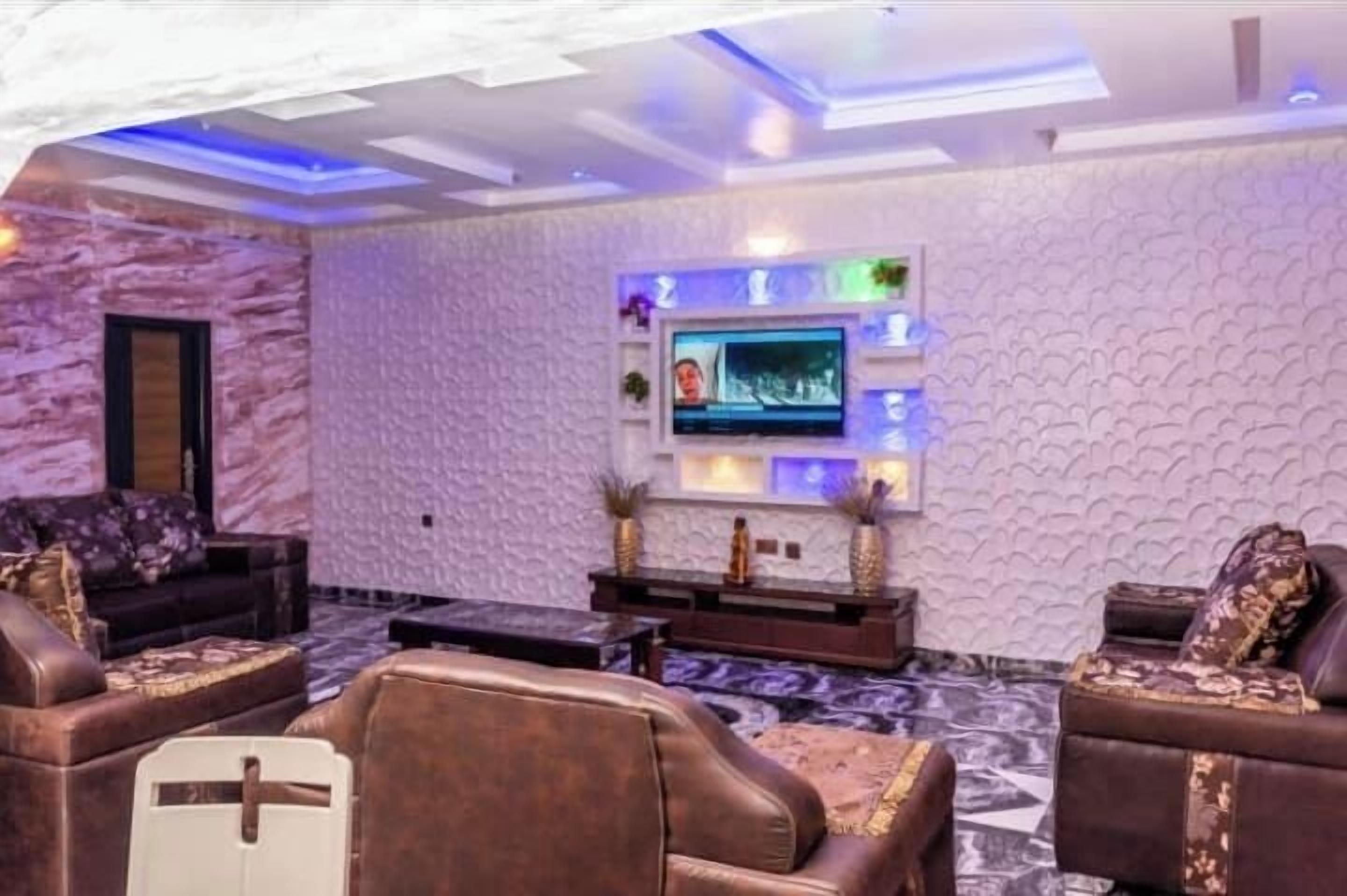 Een moderne woonkamer met een wand met marmerlook, een flatscreen televisie en leren banken.