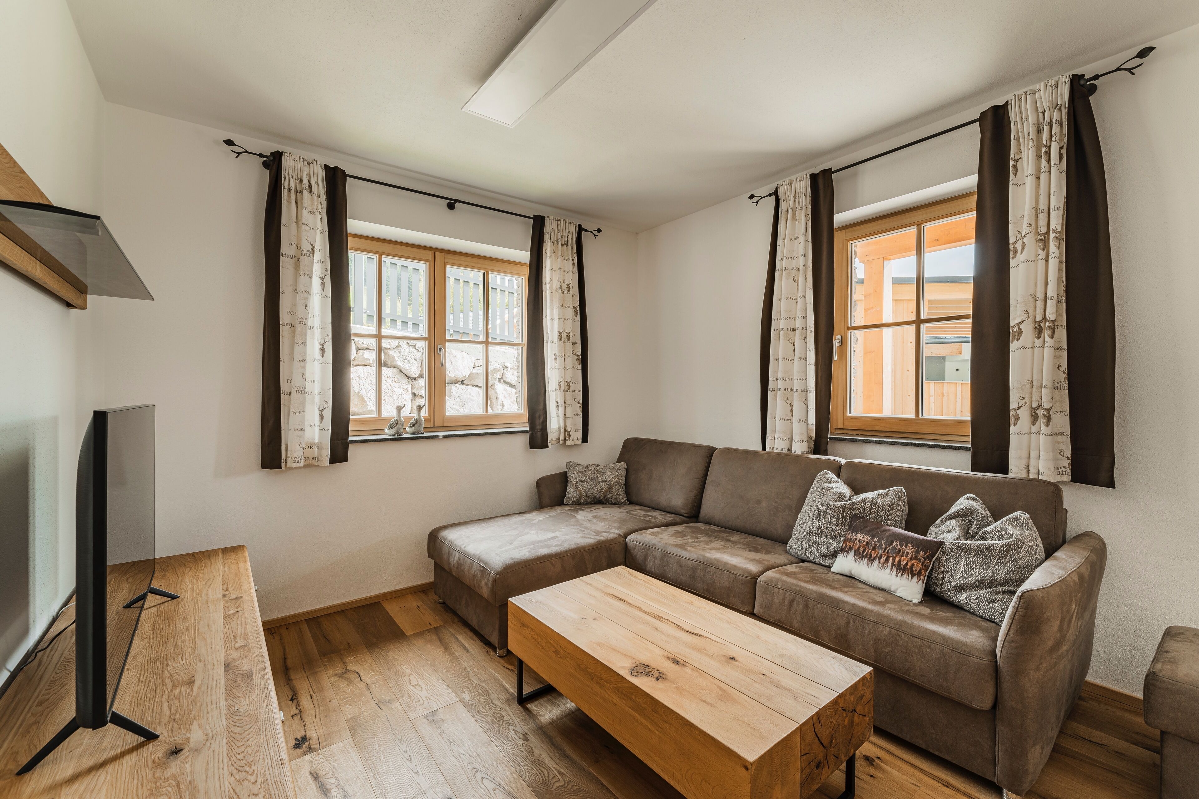 A modern living room with a sectional sofa, a wooden coffee table, and a flat-screen TV.