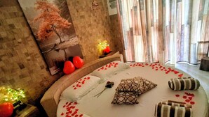Un letto circolare con petali di rosa, cuscini e un cuscino decorativo.