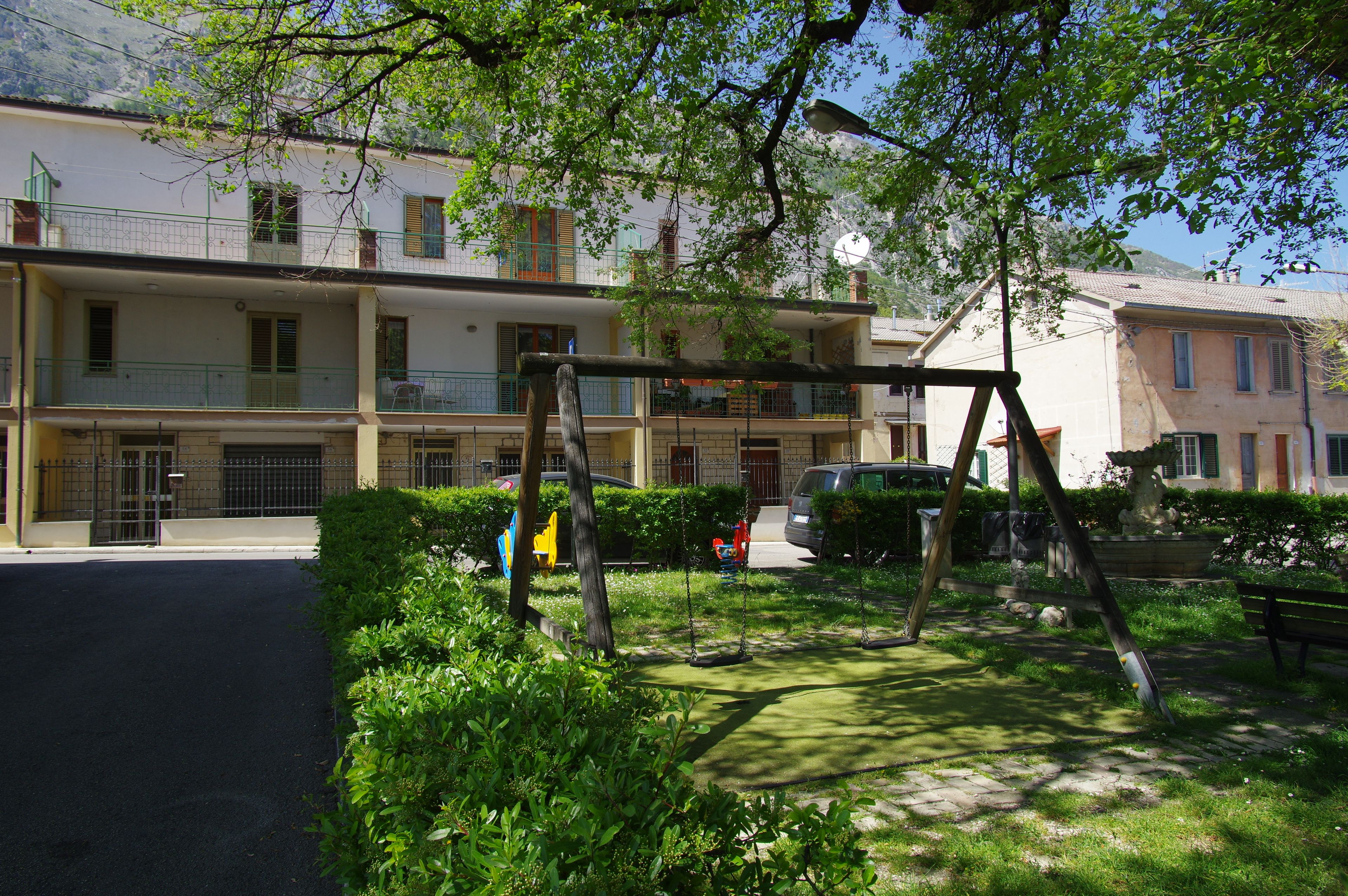 Una zona residenziale con una fila di edifici a due piani, un'altalena e un'auto parcheggiata.