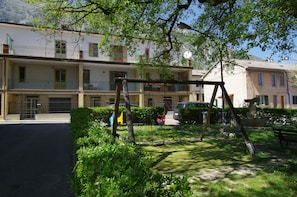 A residential area with a row of two-story buildings, a swing set, and a parked car. - Private Spa and Romantic Relaxation (Lama dei Peligni)