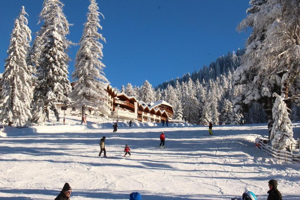 A snow-covered ski resort with a lodge, ski slopes, and snow-covered trees.