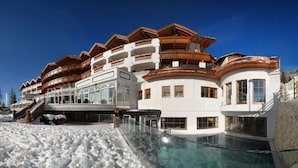 Un gran complejo turístico con múltiples balcones, una piscina y un paisaje nevado.