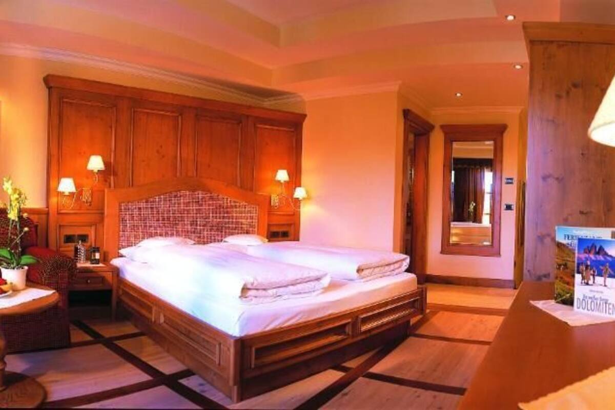 A hotel room with a double bed, a small table with a plant, a sofa, and a lamp.