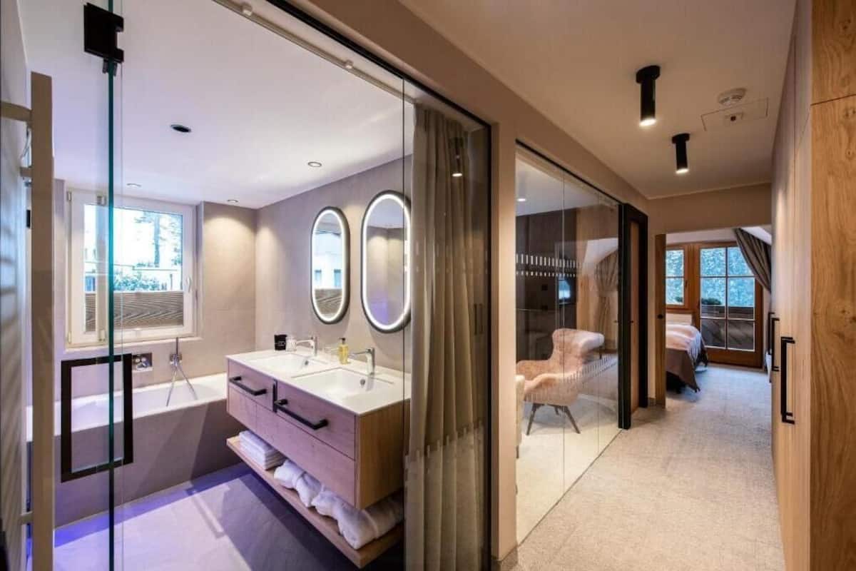 A modern bathroom with a glass shower enclosure, a double sink vanity, and a large mirror.