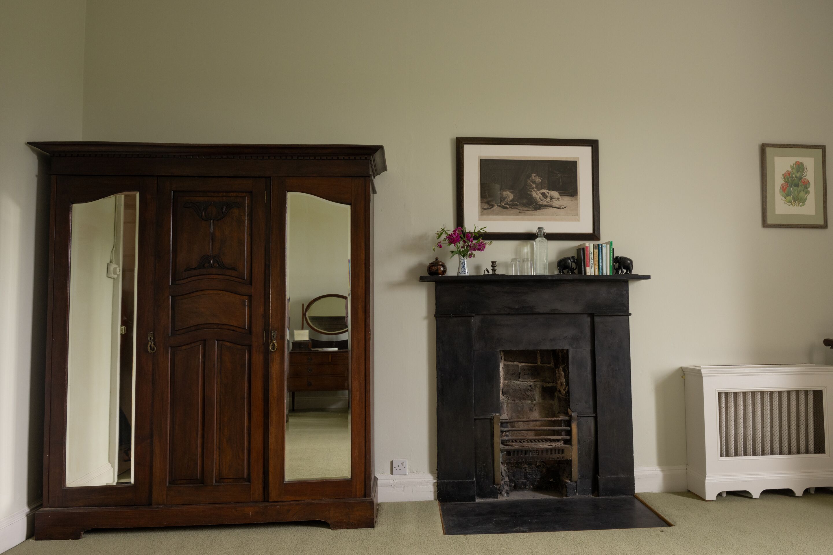 Een kamer met een houten garderobe, een open haard en een radiator.