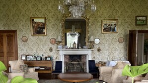 Un salón comedor tradicional con chimenea, un espejo ornamentado y muebles clásicos.