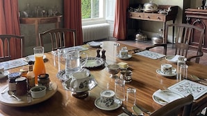 Comedor con una gran mesa de madera dispuesta para una comida, rodeado de sillas.