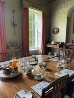 Comedor con una gran mesa de madera dispuesta para una comida, rodeado de sillas.