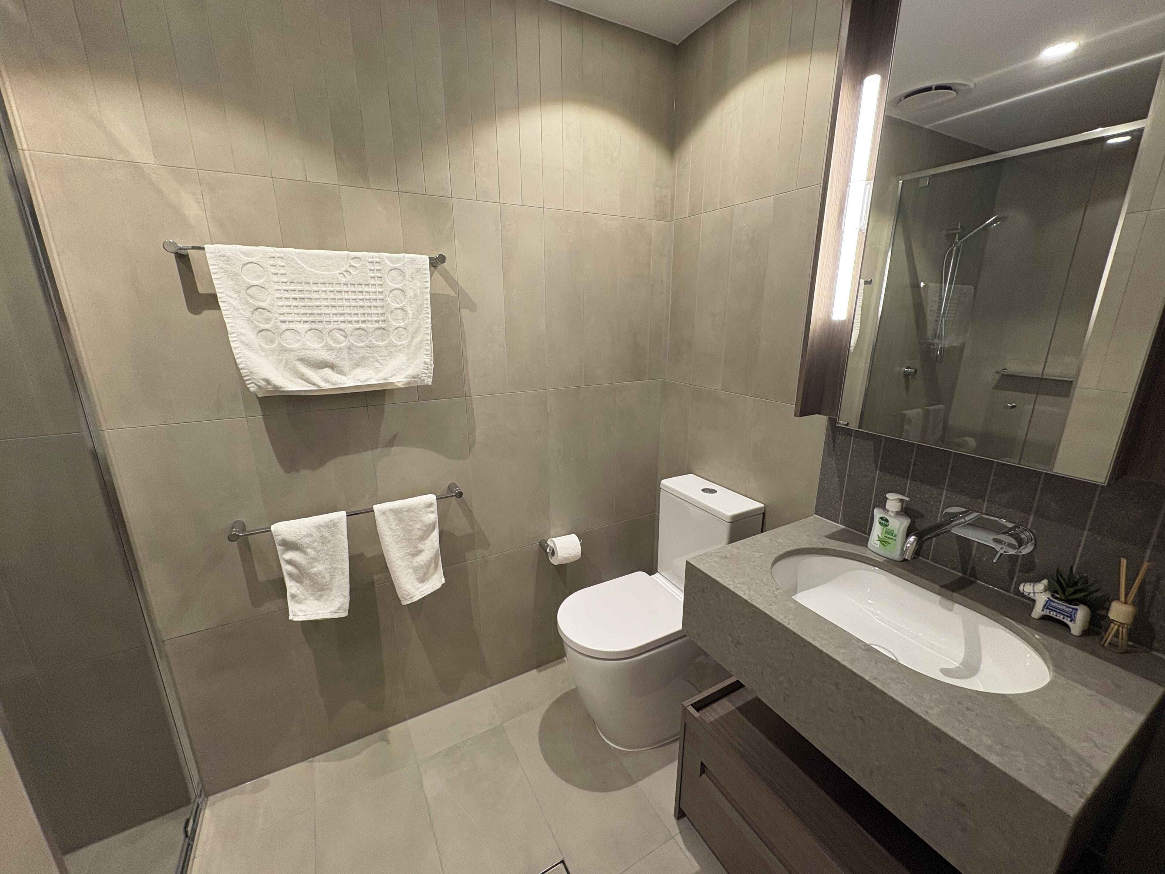 Ein modernes Badezimmer mit großem Spiegel, einer Badewanne, einer Toilette und einem Waschbecken.