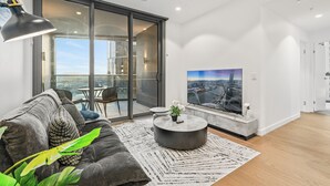 Una sala de estar moderna con un sofá gris, una mesa redonda de centro y un televisor de pantalla plana grande.
