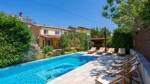 A swimming pool with lounge chairs, surrounded by greenery and a building with a tiled roof. - Villa  SANJA with pool OPATIJA by Villas Guide (Matulji)