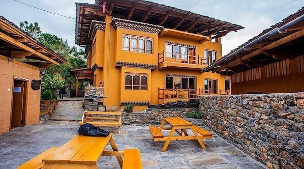 A traditional building with a stone wall and wooden benches in the courtyard.