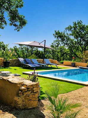 Una piscina con sillas de descanso y una pérgola.
