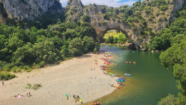 A river with boats, a beach, and a natural rock arch. - EXCEPTIONAL VIEW of Mt. Ventoux, between the Ardèche Gorges and the Cèze Valley (Salazac)