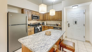 A kitchen with granite countertops, wooden cabinets, stainless steel appliances, and pendant lighting. - Poolside Bliss & Theme Park Thrills: Orlando Oasis (Orlando)