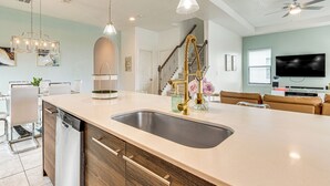 Una cocina moderna con una isla grande, electrodomésticos de acero inoxidable e iluminación colgante.