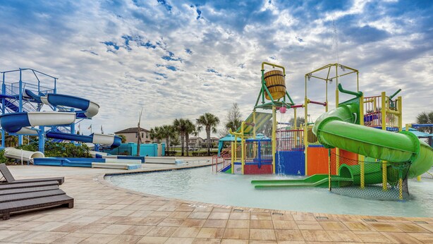Un parque acuático con piscina, toboganes y una zona de juegos.