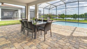 Un patio cubierto con una mesa y sillas de comedor, una piscina y vistas a un lago.