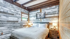 A bedroom with a wooden slat wall, a bed with white bedding, two bedside tables with lamps, and a framed picture above the bed. - Farmhouse Hideaway w/ Covered Patio in Kissimmee (Kissimmee)
